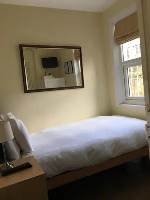 a bedroom with a bed with a mirror on the wall at Lincoln Guest House in Keswick
