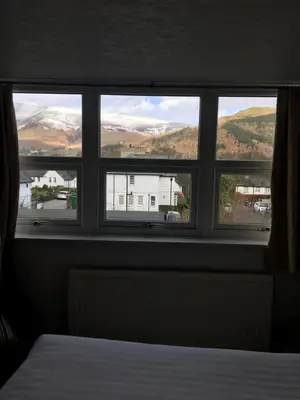 a window with views of a house and mountains at Lincoln Guest House in Keswick