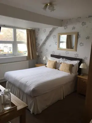 a bedroom with a large white bed and two windows at Lincoln Guest House in Keswick