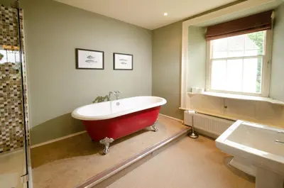 a bathroom with a red bath tub and a window at Eltermere Inn in Elterwater
