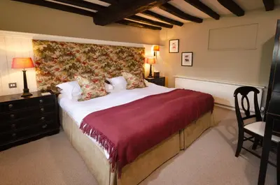 a bedroom with a large bed and a chair at Eltermere Inn in Elterwater