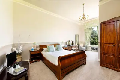 a bedroom with a bed and a dresser and a desk at The Greenhill Hotel in Wigton