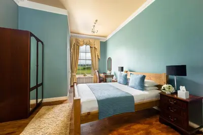 a bedroom with a large bed with blue walls at The Greenhill Hotel in Wigton