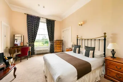 a bedroom with a bed and a desk and a window at The Greenhill Hotel in Wigton