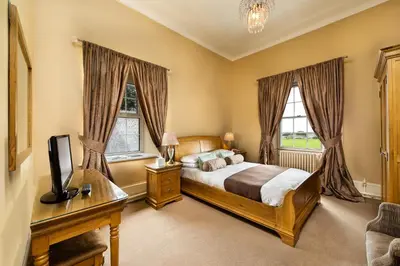 a bedroom with a bed and a tv and windows at The Greenhill Hotel in Wigton