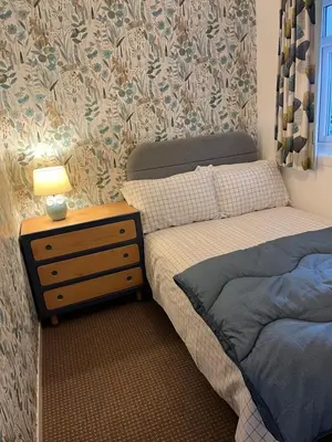 a small bedroom with a bed and a night stand at Pottery Cottage, Lochans Lodge in Stranraer