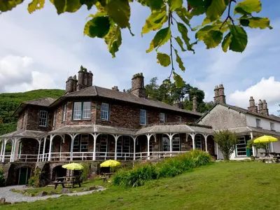 a large brick house with yellow umbrellas in front of it at YHA Langdale in Ambleside
