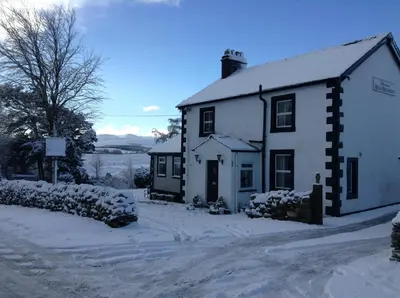 a white house with snow on the ground at Netherdene Country House Bed & Breakfast in Troutbeck