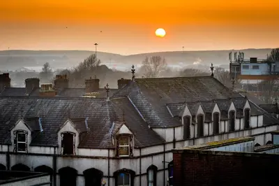 an old building with the sun setting in the background at Washington Central Hotel and Sleepwell Inn in Workington