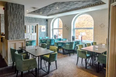 a restaurant with tables and chairs in a room at Washington Central Hotel and Sleepwell Inn in Workington