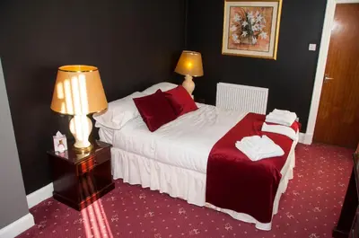 a bedroom with a bed and a table with a lamp at Caledonian Hotel in Dumfries
