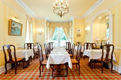 a dining room with tables and chairs and a chandelier at Bridge Hotel in Buttermere