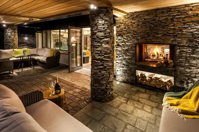 a fireplace in a living room with a stone wall at Langdale Hotel & Spa in Ambleside