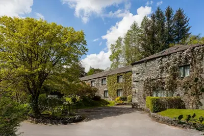 an old stone house with a tree and a driveway at Langdale Hotel & Spa in Ambleside