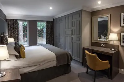 a hotel room with a large bed and a desk and window at Langdale Hotel & Spa in Ambleside