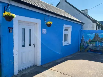 a blue building with a white door and flowers at Marina Studio in Irvine