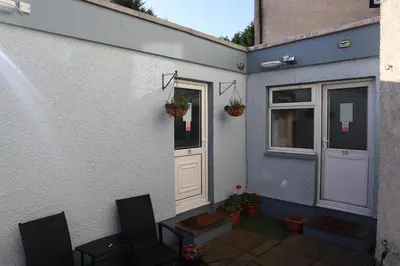 a house with a door and a table and chairs at Harbourside Hotel in Irvine