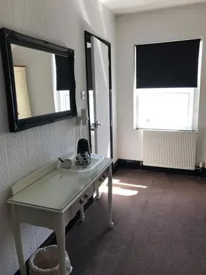 a room with a table and a mirror and a window at Edelweiss Guest House in Douglas