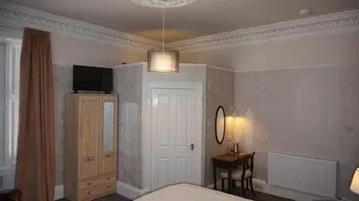 a bedroom with a bed and a table and a mirror at Lindean Guest House in Dumfries
