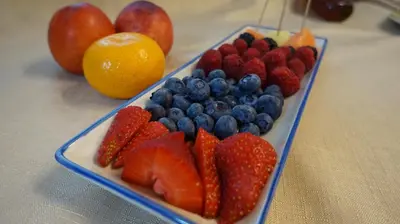 a plate of fruit on a table with strawberries and blueberries at Lindean Guest House in Dumfries