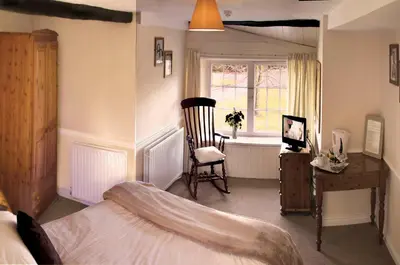 a bedroom with a bed and a chair and a window at Boot & Shoe Inn in Greystoke
