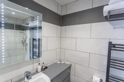 a white bathroom with a sink and a mirror at The Sally in Carlisle