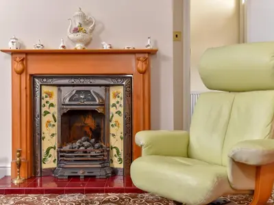a yellow chair sitting next to a fireplace at The Warren Guest House in Carlisle
