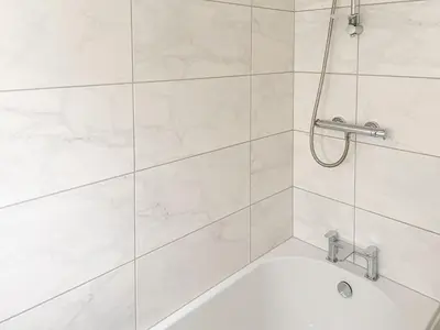 a white bathroom with a tub and a shower at Jasmine Cottage in Keswick