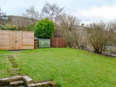 a backyard with a wooden fence and a grass yard at Katellen Cottage in Threlkeld