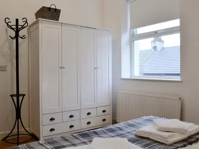 a bedroom with a bed and a large white cabinet at Katellen Cottage in Threlkeld
