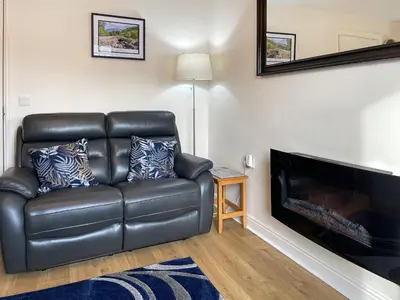 a black leather couch in a living room with a fireplace at High Views in Keswick