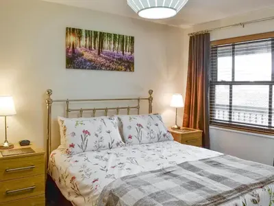 a bedroom with a bed and two lamps and a window at High Views in Keswick