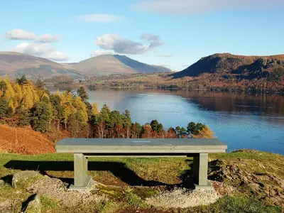 a bench sitting on top of a hill overlooking a lake at High Views in Keswick