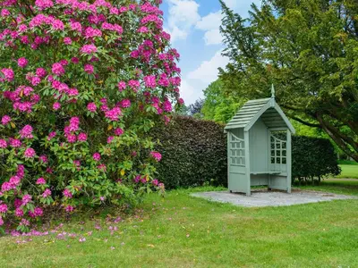 a small bird house in a garden with pink flowers at The Old Stables in Sorn