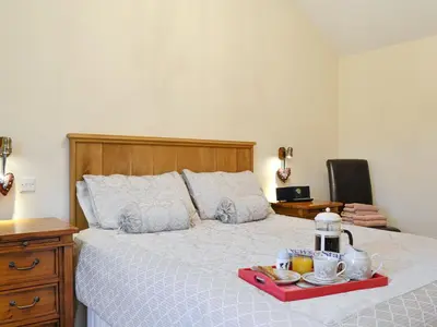 a bedroom with a bed with a tray of food on it at Little Meadow in Dearham