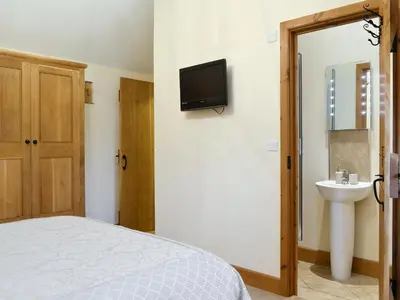 a bedroom with a bed and a sink and a tv at Little Meadow in Dearham