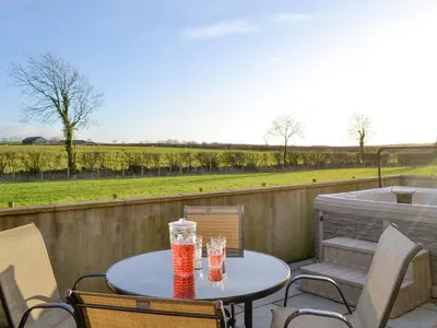 a table and chairs on a patio with a view of a field at Little Meadow in Dearham