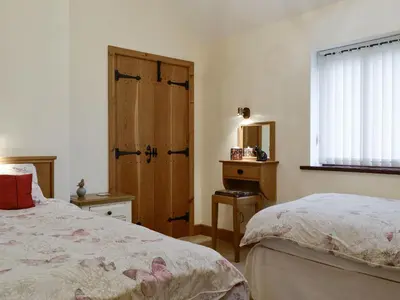 a bedroom with two beds and a wooden door at The Old Byre in Dearham