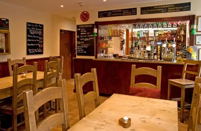 a restaurant with wooden tables and chairs and a bar at New Dungeon Ghyll Hotel in Great Langdale