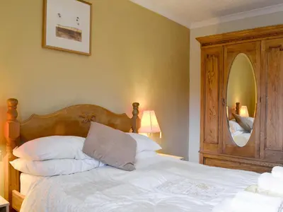 a bed with a wooden headboard and a mirror at Bianca Rose in Keswick