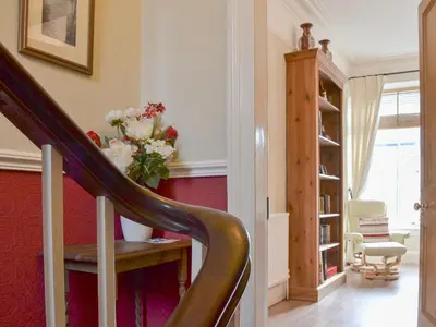 a hallway with a staircase with a vase of flowers at Bianca Rose in Keswick