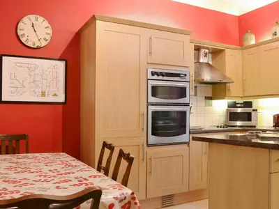 a kitchen with a table and a clock on the wall at Bianca Rose in Keswick