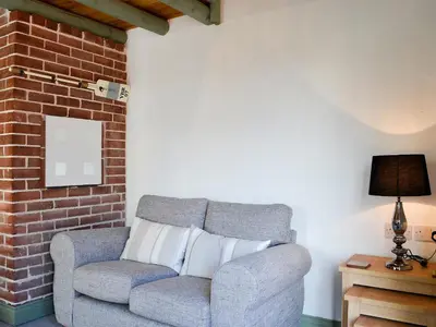a gray couch sitting next to a brick wall at Lucy's Lodge - Uk1260 in Threlkeld