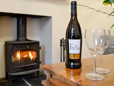 a bottle of wine and a glass on a table with a stove at Gilbert's Warrant in Keswick