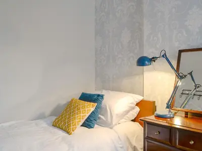 a bedroom with a bed with a lamp and a mirror at Gilbert's Warrant in Keswick