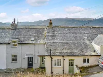 an old white house with a roof with mountains in the background at The Tottsie in Bassenthwaite