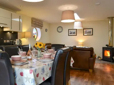 a dining room with a table with plates and chairs at Porthole Cottage in Allonby