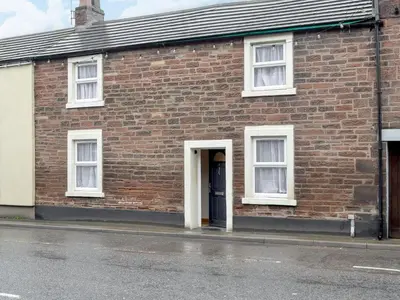 a brick building with a door and windows at Brodie Cottage in Aspatria