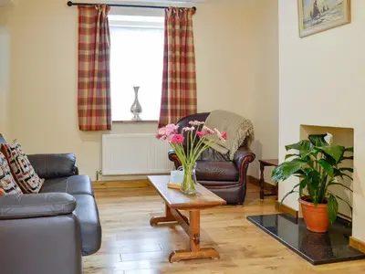 a living room with a couch and a table with flowers at Brodie Cottage in Aspatria