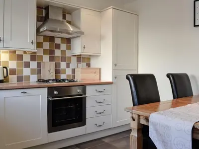 a kitchen with white cabinets and a table with chairs at The Costins in Allonby